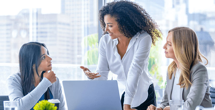A guy with glasses is presenting some paperwork to an older couple, and they’re all smiling.